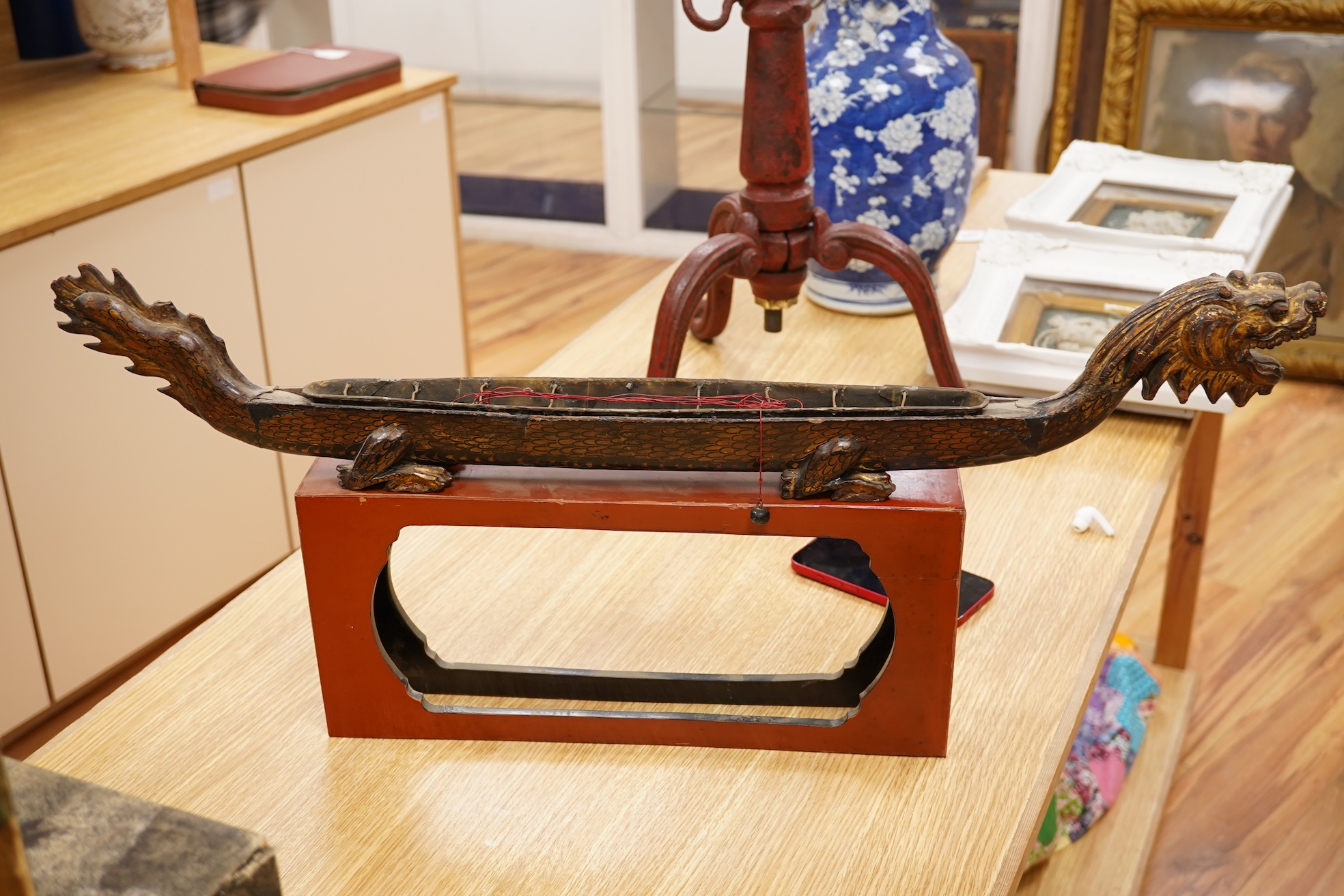 A South East Asian gilt decorated black lacquer model 'dragon' boat on stand, 75cm
